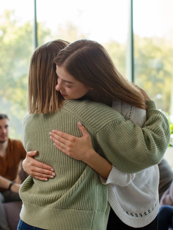 Two women supporting each other in a substance use disorder drug rehab center.